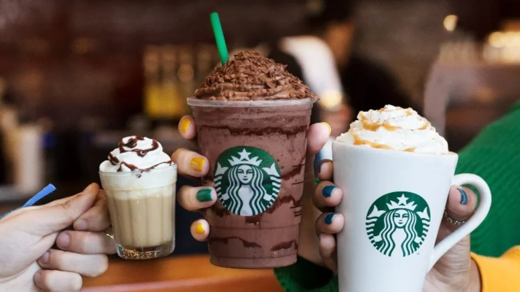 Fotografia de três pessoas com produtos starbucks dando evidência a marca e logotipo da empresa, como um bom trabalho de branding.